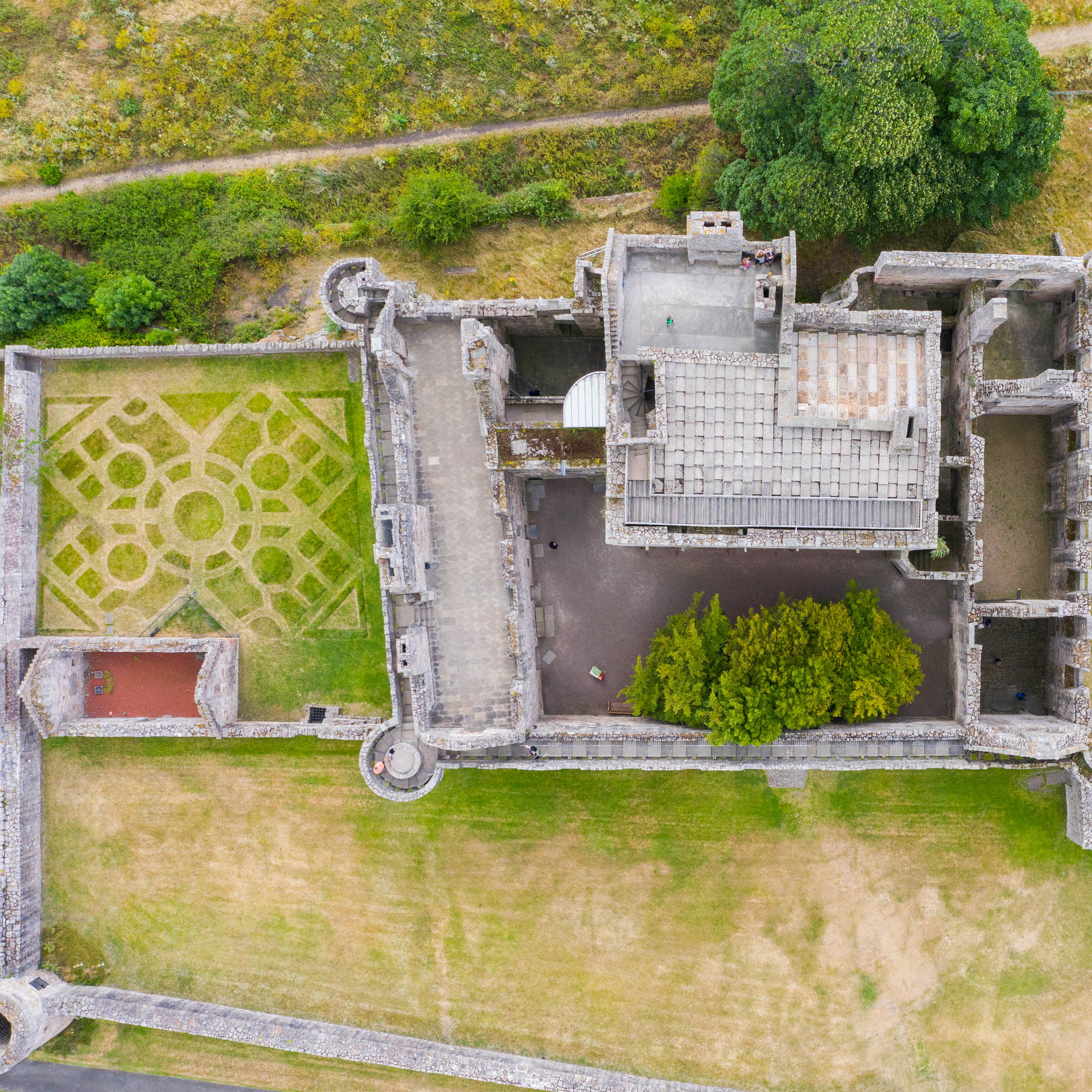 Overhead aerial view focusing on the inner buildings and courtyards of Craigmillar Castle, with patterned garden beds and stone structures clearly visible.
