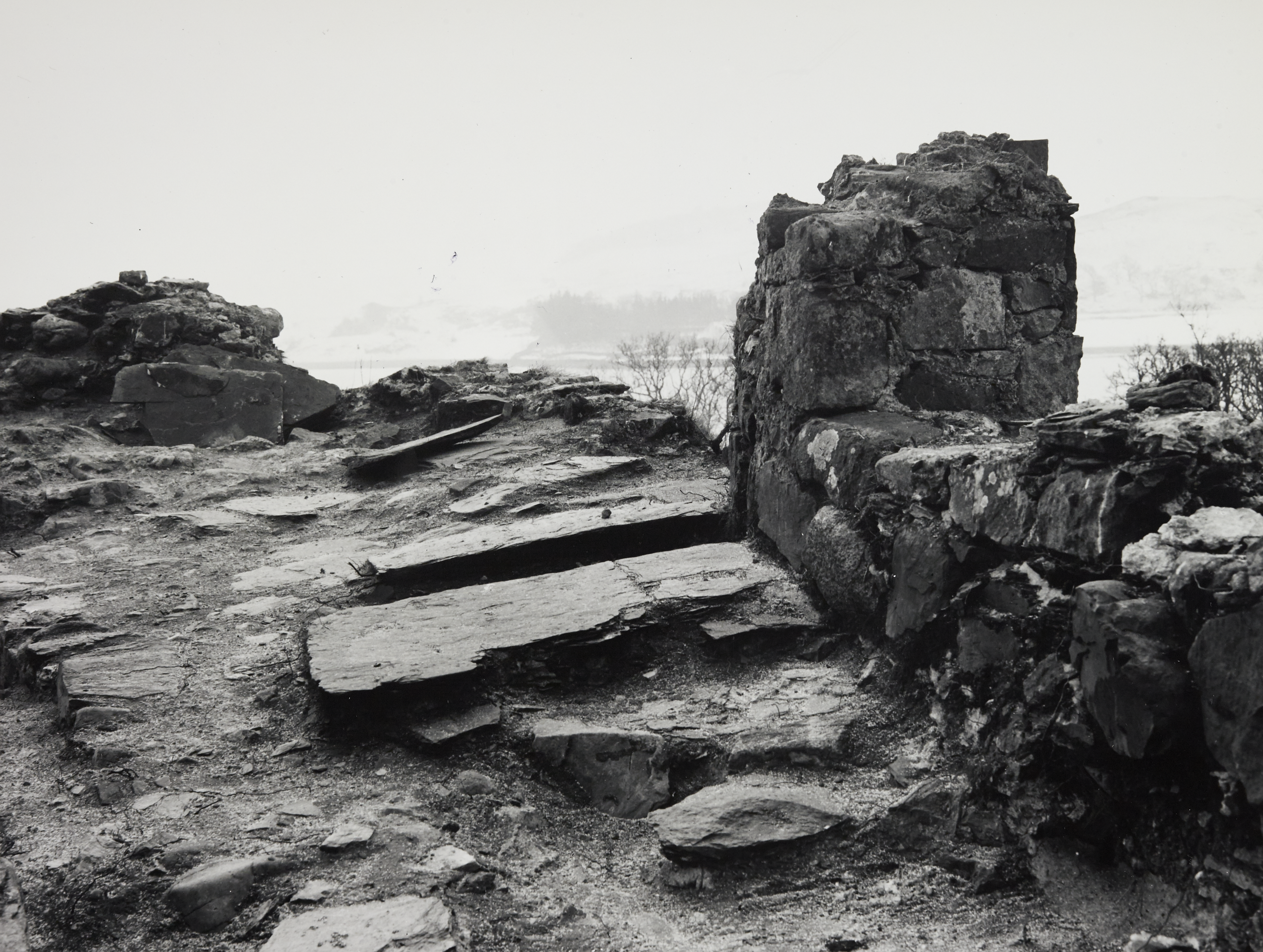 Black and white image of a part of a wall at the top of a hill, perhaps