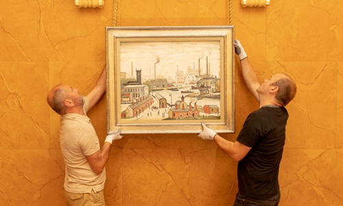 two men hang the painting 'Canal and Factories' on a wall
