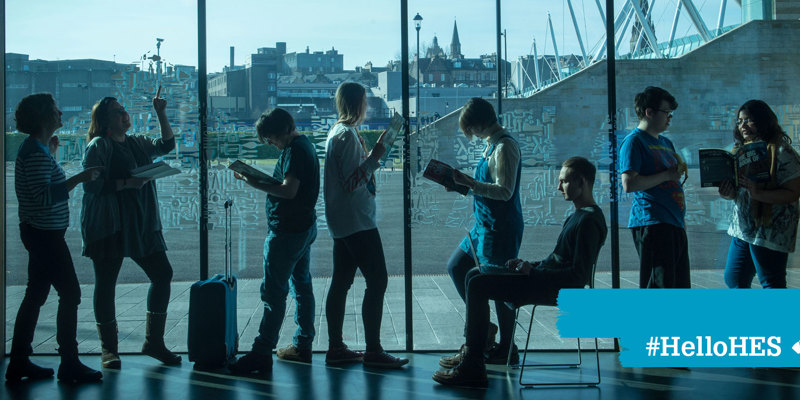 8 people standing in front of a large window