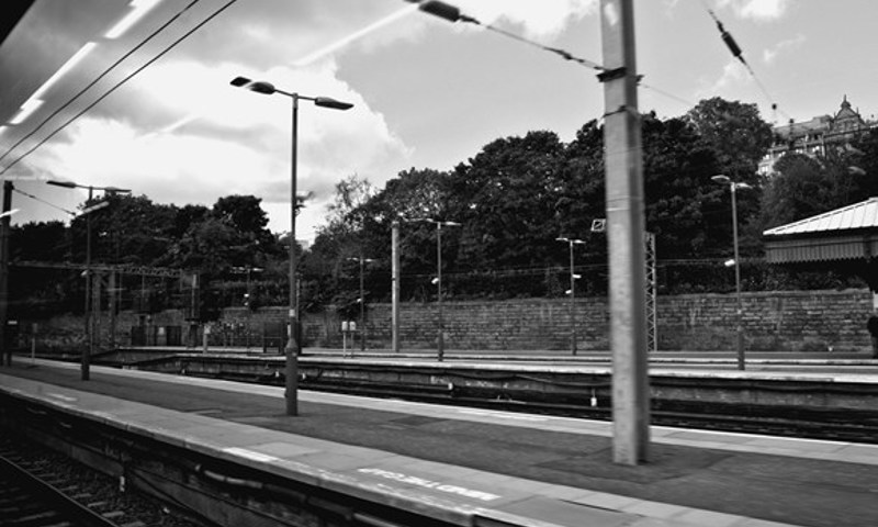 A black and white photograph of a deserted railway station. 