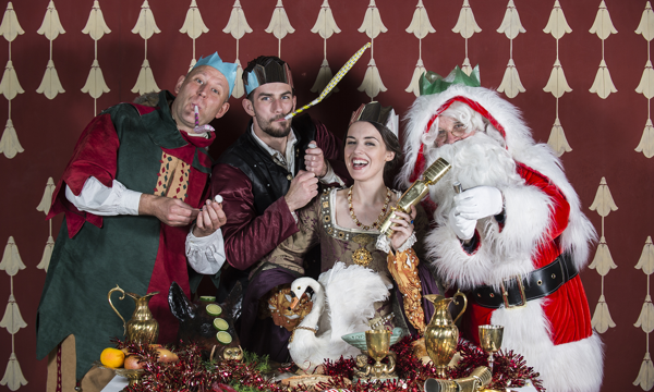 A merry group of people in medieval dress celebrate with Santa