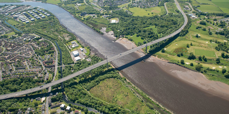 A large bridge over a river on a partially cloudy day.