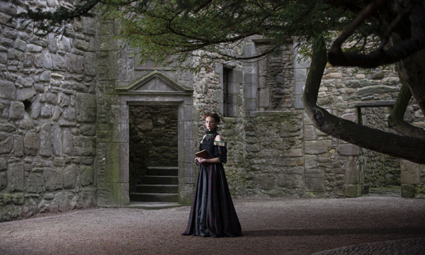 A woman in a Mary Queen of Scots inspired dress stands in the courtyard at Craigmillar Castle