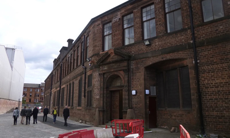 A community group walk beside a large former industrial building in Govan as part of a regeneration project