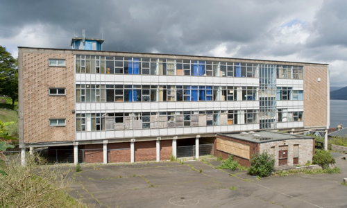 A flat-topped school building with a large number of windows on a cloudy day.