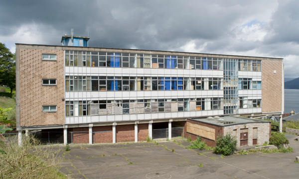 A flat-topped school building with a large number of windows on a cloudy day.