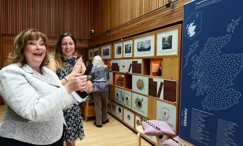 Two smiling women enjoy a Scotland's Urban Past exhibit