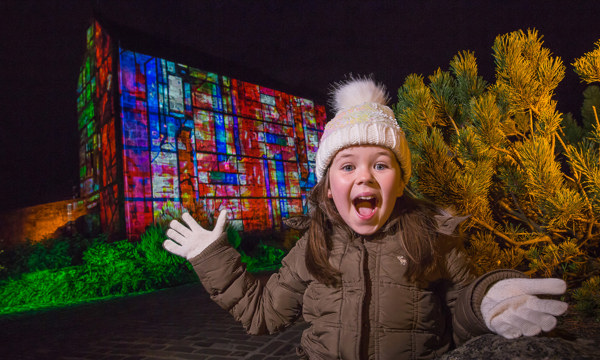 Excited girl in front of projection on to St Margaret's Chapel at Edinburgh Castle