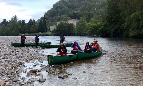 Several women and guides canoe on a river