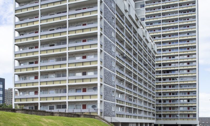 A high rise block of flats with cars parked outside