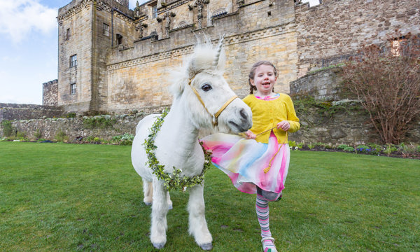 Girl in the Queen Anne Garden at Stirling Castle with a pony with a unicorn and neck garland
