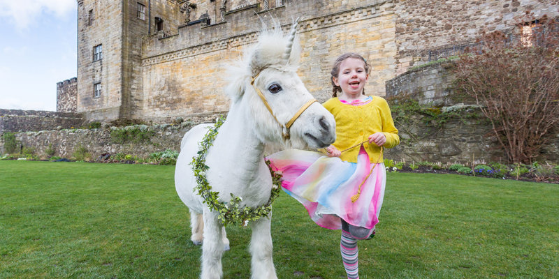 Girl in the Queen Anne Garden at Stirling Castle with a pony with a unicorn and neck garland