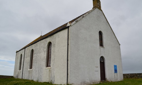 a plain-looking whitewashed church with slate roof