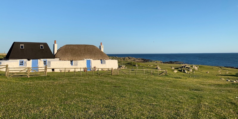 small whitewashed thatched cottage by the sea. 
