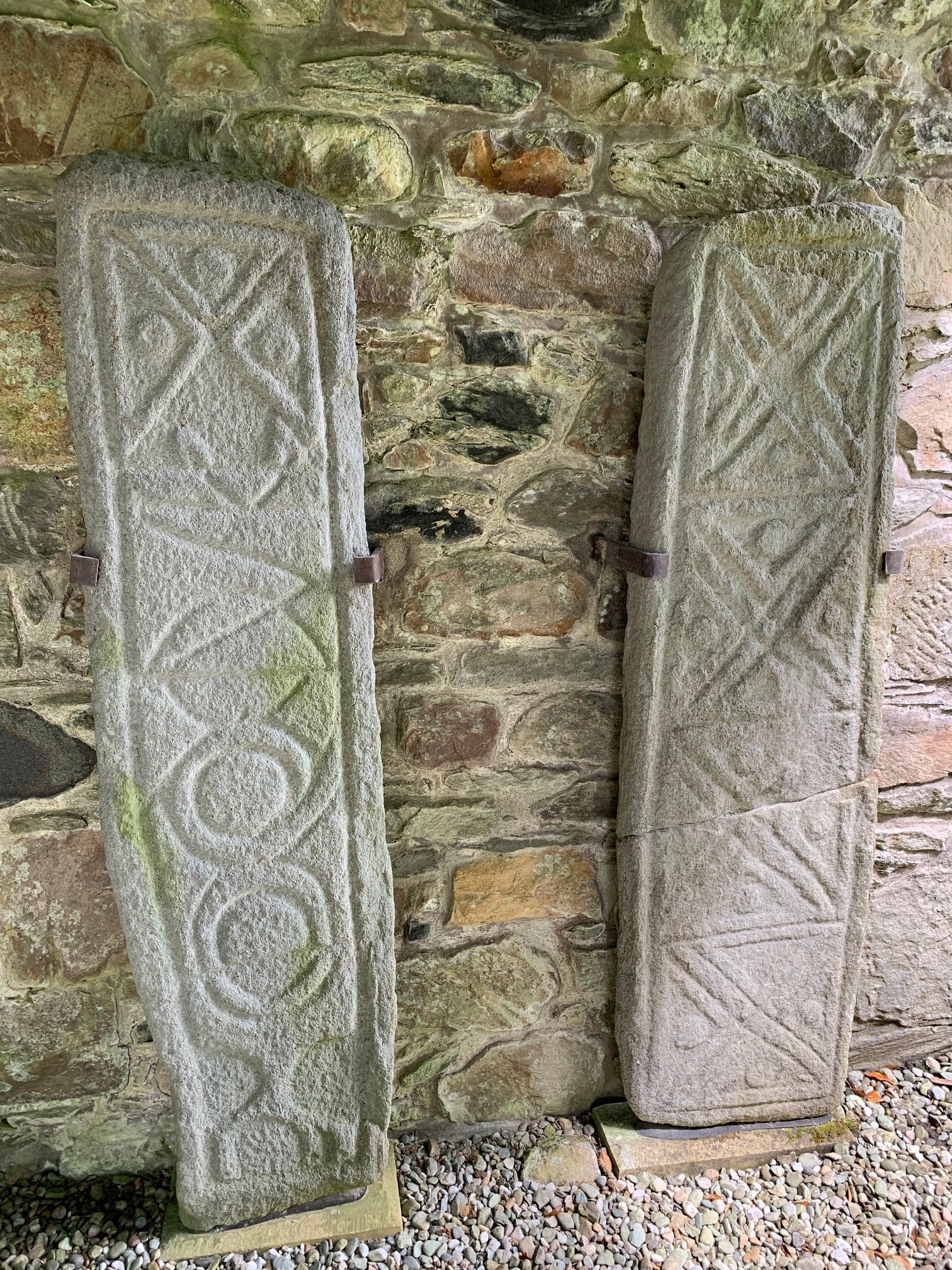 Two sculptured stone slabs with a wall behind them. 