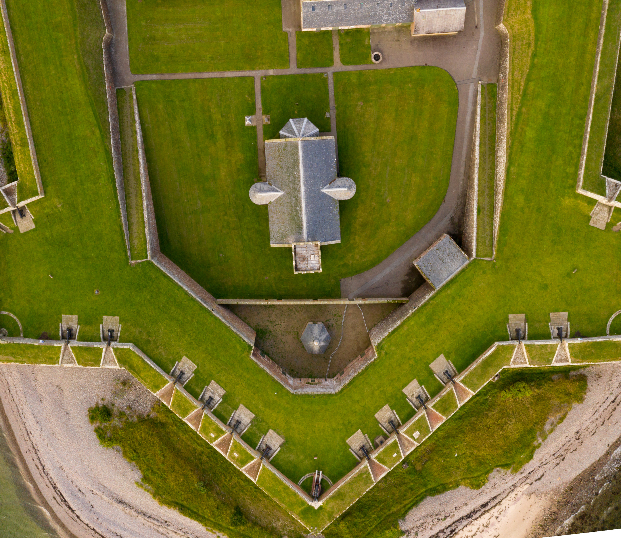 A top‑down aerial view of the fort’s angular defensive walls, grassy ramparts, and a central stone building near the shoreline.