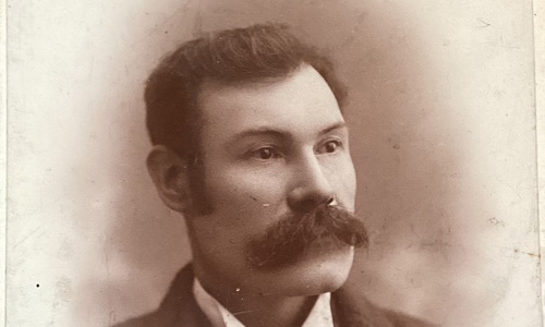Old, sepia-toned portrait photograph of Andrew Baird. He is well dressed with dark hair and a large moustache.