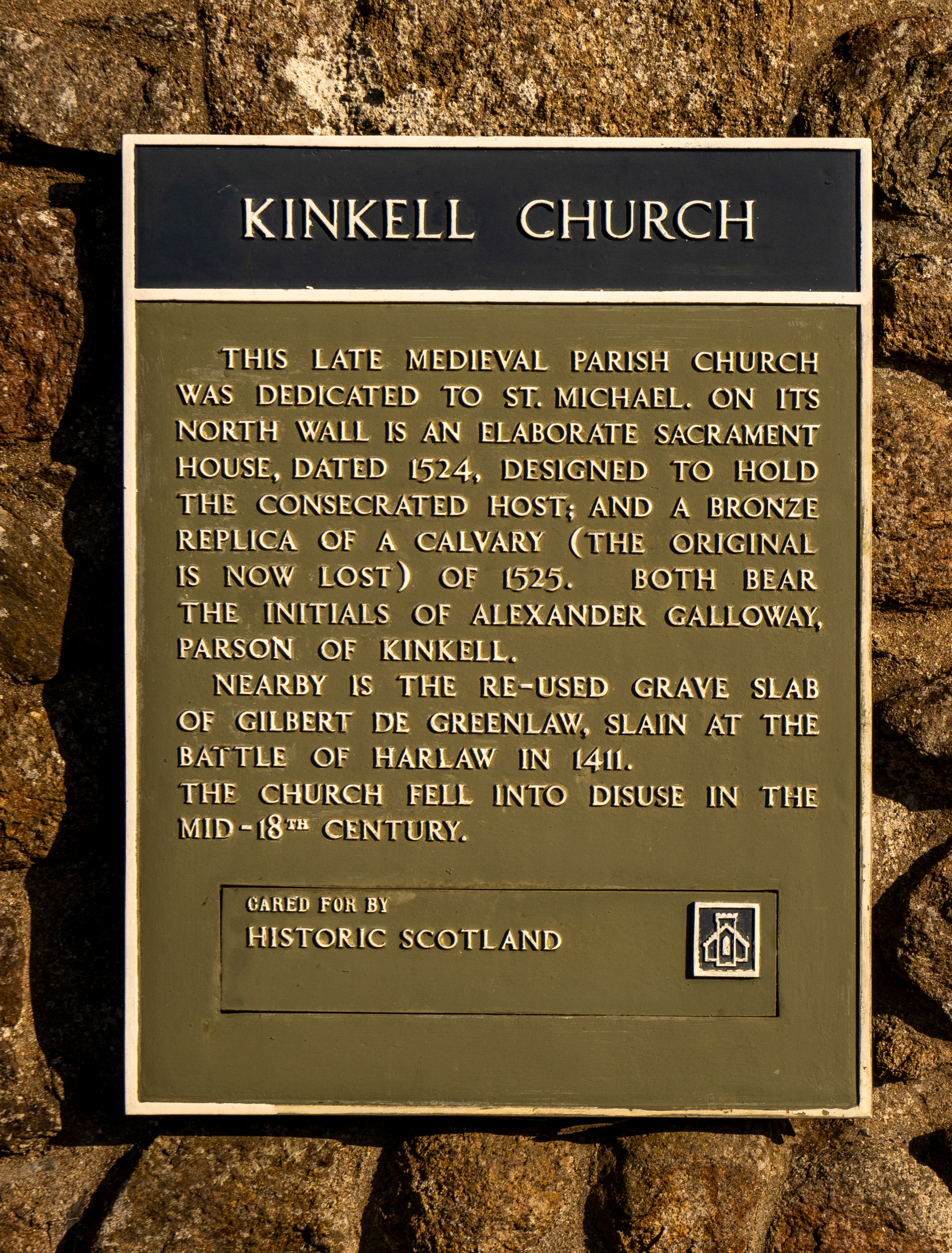 Information sign for Kinkell Church mounted on a stone wall, describing the site’s medieval history.