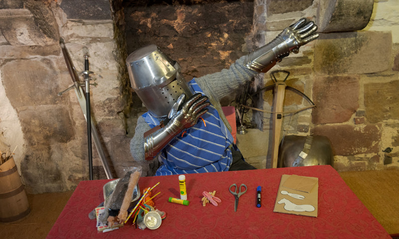 Learning Producer, Cat Hood, wearing a knight helmet and gaunlets for the educational Craft Knights video at Edinburgh Castle