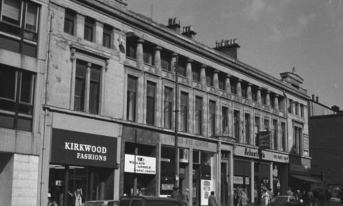 A black and white photo of a block of traditional buildings and shops