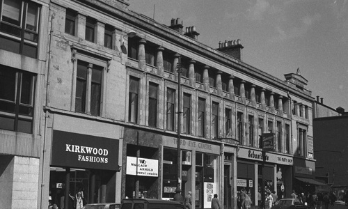 A black and white photo of a block of traditional buildings and shops
