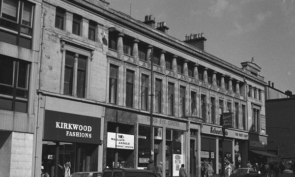 A black and white photo of a block of traditional buildings and shops