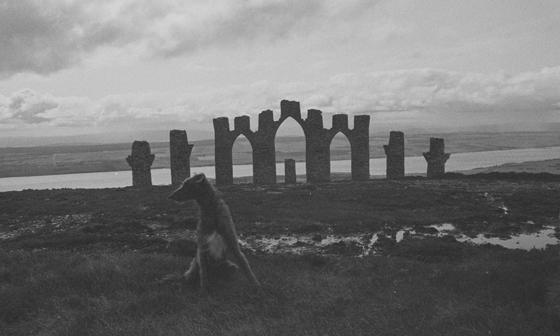 A monument of stone archways on a hill in the countryside