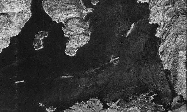 An aerial view of large ships surrounded by mountains.