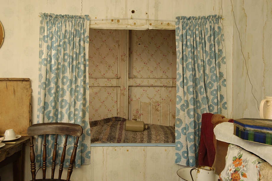 A bed cut into the recess of a wall, framed with curtains