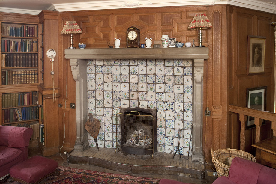 A mantlepiece with patterned tiles, and lamps and ornaments sitting on top of it