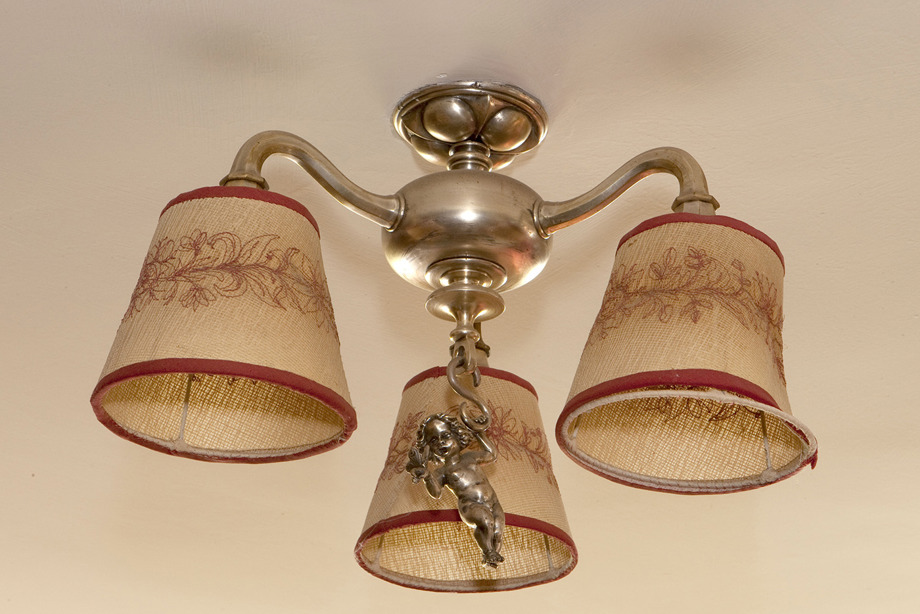 A ceiling light with a golden cherub design, and lampshades embroidered with floral patterns