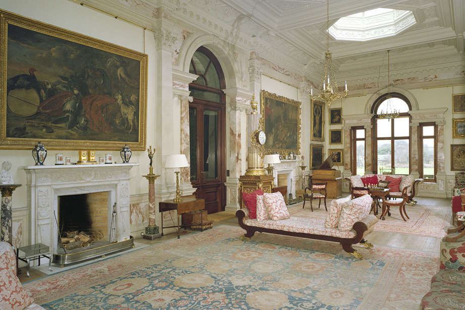 A room with marble doors and windows, patterned furniture and carpet, and large paintings on the walls