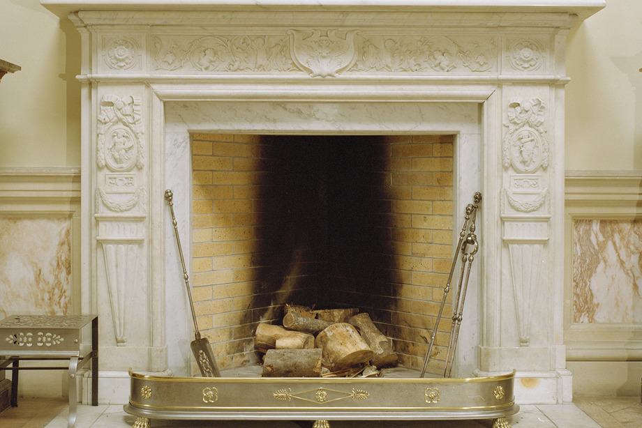 A decorative white fireplace, with vases and ornaments on top