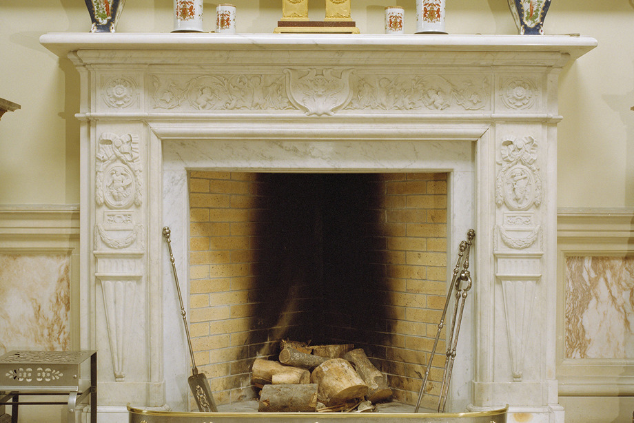 A decorative white fireplace, with vases and ornaments on top