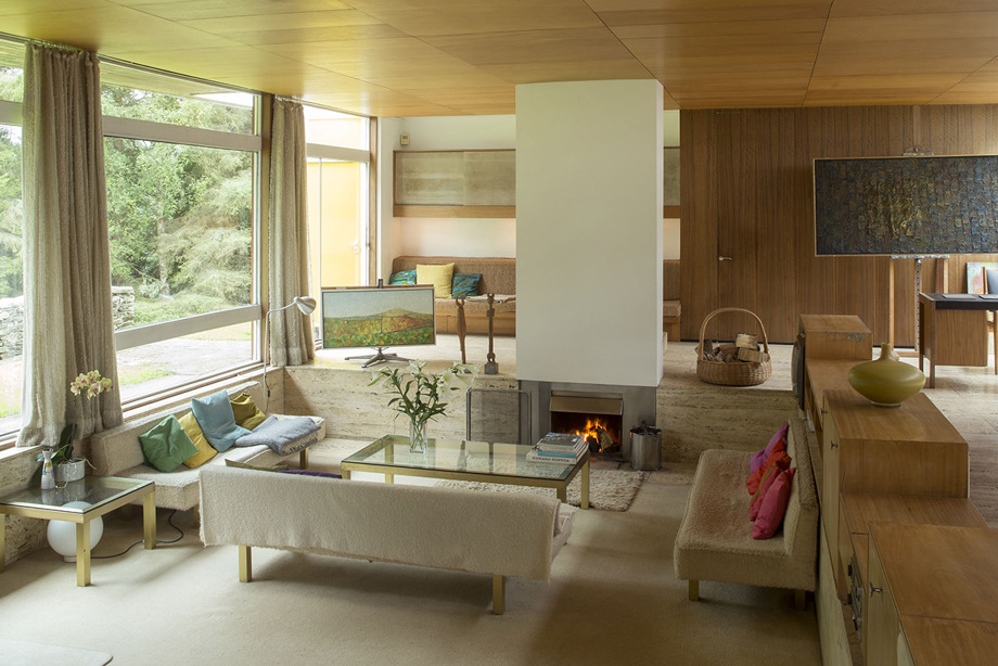 A lliving room with several sofas, a fireplace and large windows
