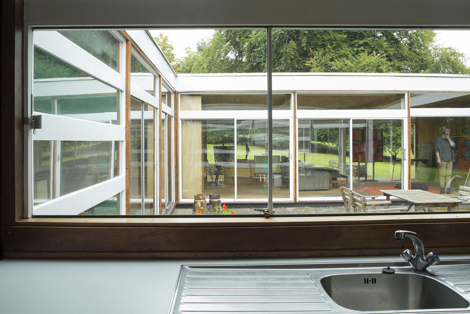 A kitchen sink area, with long windows, looking out into a courtyard and other sides of the building