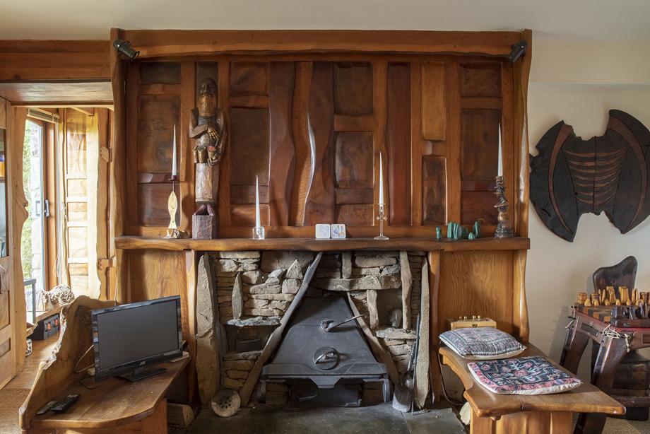 A carved, wooden cabinet above a stone fireplace, Carved wooden furniture sits in front of the fireplace