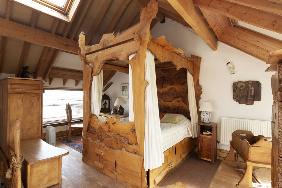 A bedroom with wooden furniture and a carved wooden four-poster bed in the centre of the room