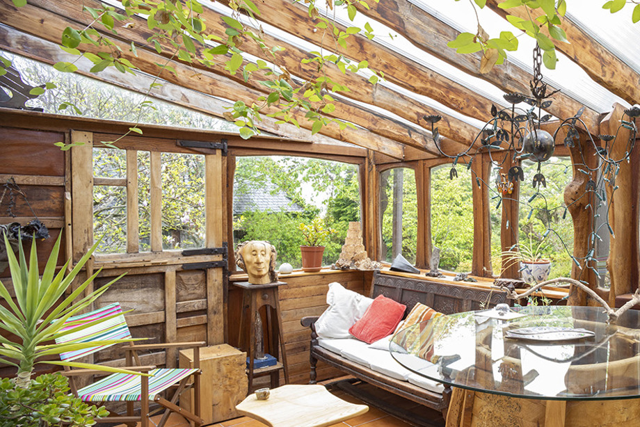 A wooden and glass room, with chairs and wooden sculptures