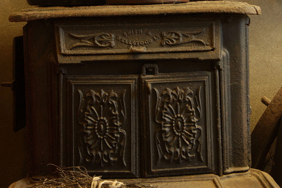 Kettles and pots sit on top of a dark cast iron stove