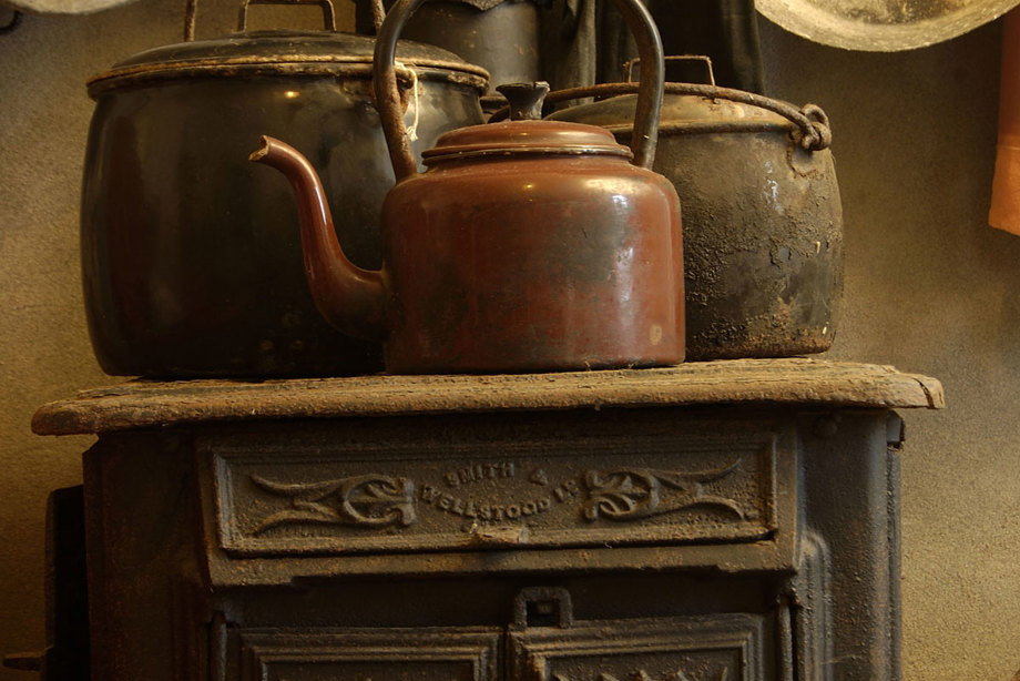 Kettles and pots sit on top of a dark cast iron stove