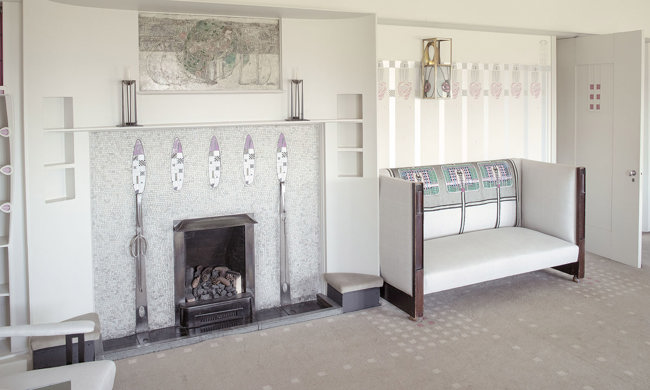 A white armchair beside a white mosaic fireplace