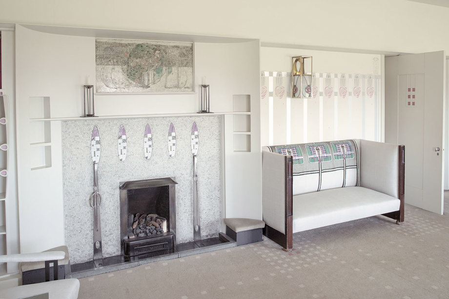 A white armchair beside a white mosaic fireplace