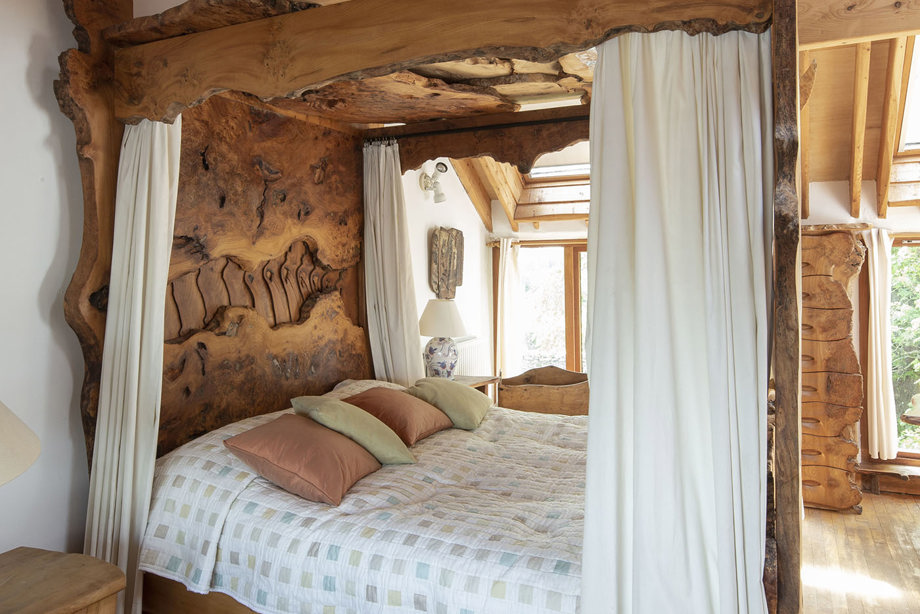 A carved, wooden four-poster bed with white drapes