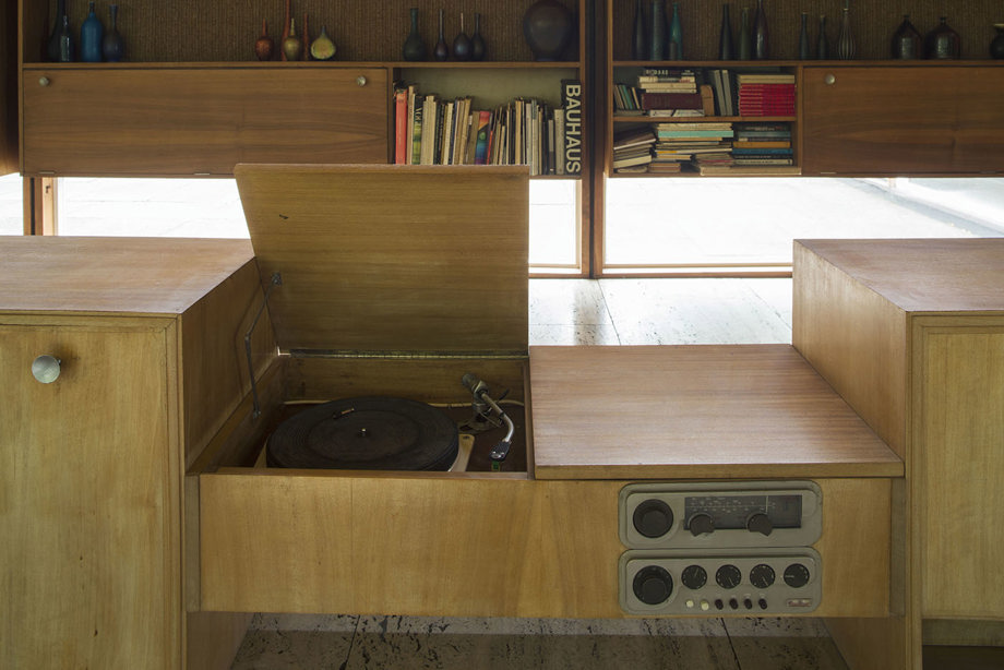 A wooden record player, in front of wooden shelves lined with books