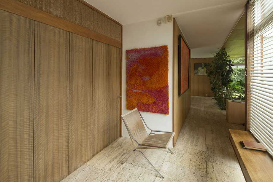 A hallway with a wooden clad wall, silver chair and tall plant in a pot