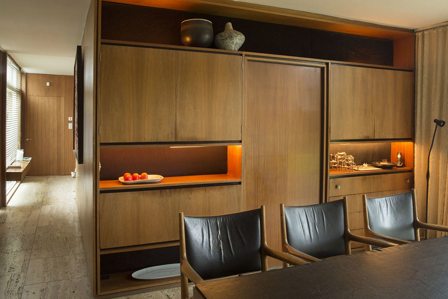 A dining room with wooden wall cabinets, a table, and leather-backed wooden chairs