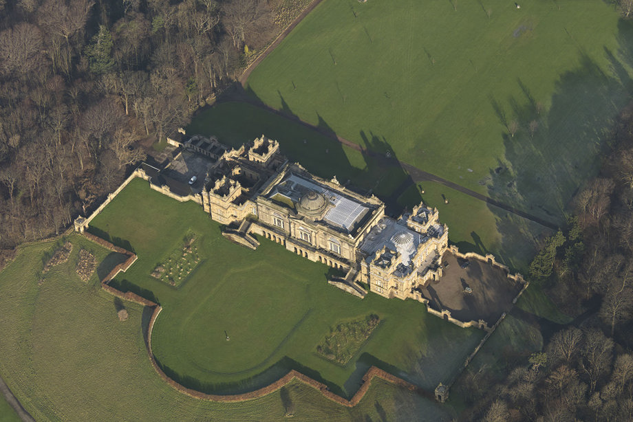 An aerial view of a large, stone mansion in the middle of the countryside