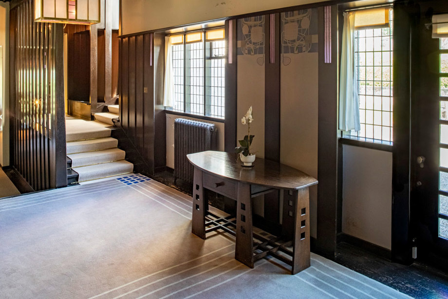 A room with a decorative carpet and a small, carved wooden table